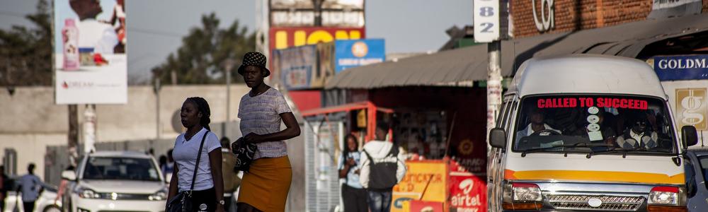 Two women waling across a car road in Zambia.