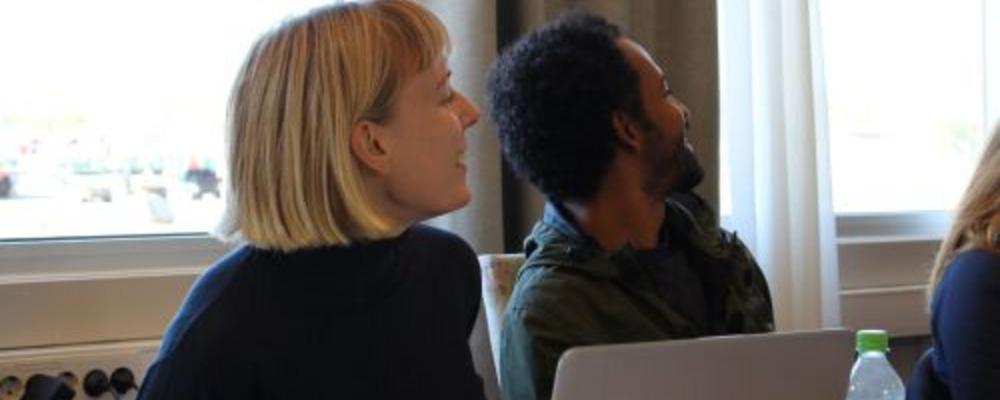 Blonde woman next to dark-haired man looking at something to the right off-screen. 